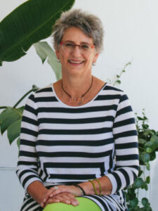 Amy Posner, Conversion Copywriter and Copy Chief sits with hands folded wearing a striped top